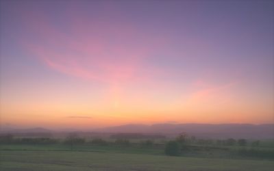 Scenic view of field against orange sky