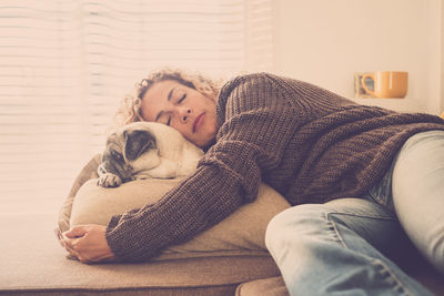 Woman sleeping by pug in living room at home