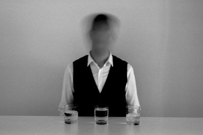 Full length portrait of a man sitting on table against wall