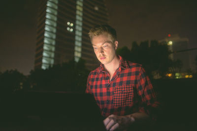 Young man looking at camera at night