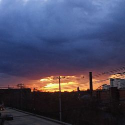 Silhouette city street against sky during sunset