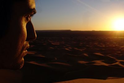 Close-up of man at desert against sky during sunset