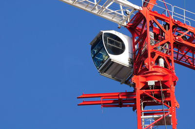 Low angle view of crane against clear blue sky