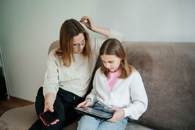 Mom helps daughter teenager with lessons uses tablet for learning