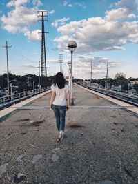 Rear view of woman on road against sky