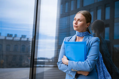 Business woman with folder in hand near office building