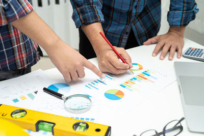 Midsection of real estate agent and colleague working on blueprint