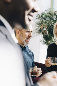 Mature businessman having coffee with colleagues in meeting at office conference