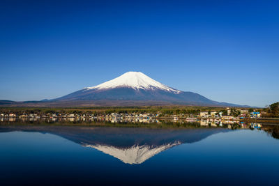 Mount fuji or fujisan with skyline reflection from yamanaka lake against blue sky, yamanashi