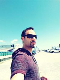 Portrait of young man wearing sunglasses standing on beach