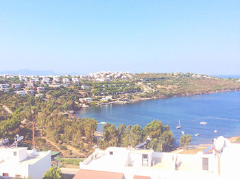 High angle view of townscape by sea against clear sky