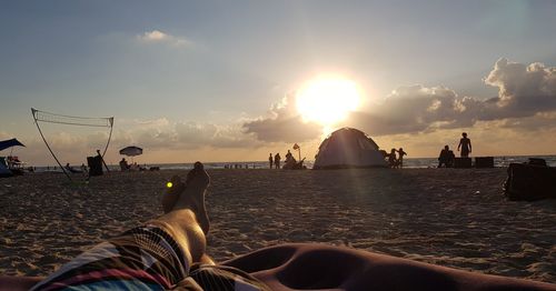 People on beach against sky during sunset