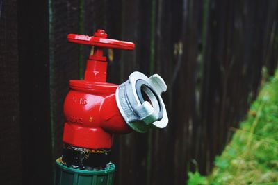 Close-up of red fire hydrant against wooden fence