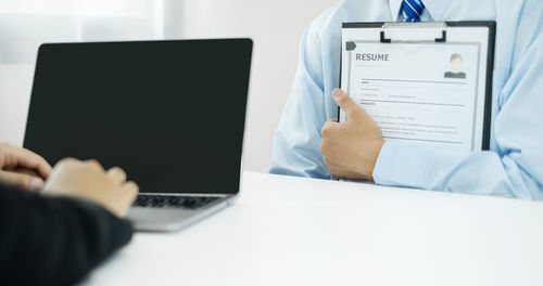 Cropped hands of woman using digital tablet on table