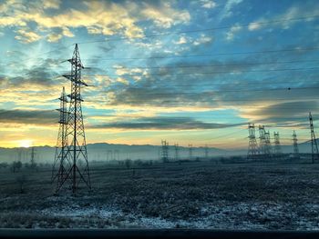 Silhouette electricity pylon against dramatic sky