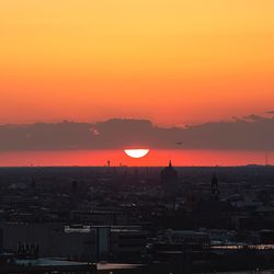 Silhouette city against orange sky