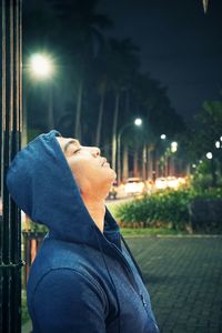Side view of man looking at illuminated city street