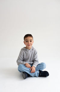 Portrait of cute boy sitting against white background