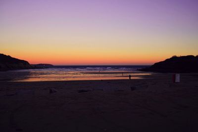 Scenic view of beach against clear sky during sunset