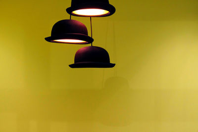 Low angle view of illuminated pendant lights against wall