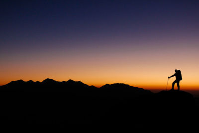 Silhouette man standing on mountain against sky during sunset