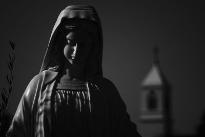 Low angle view of virgin mary statue by church against clear sky