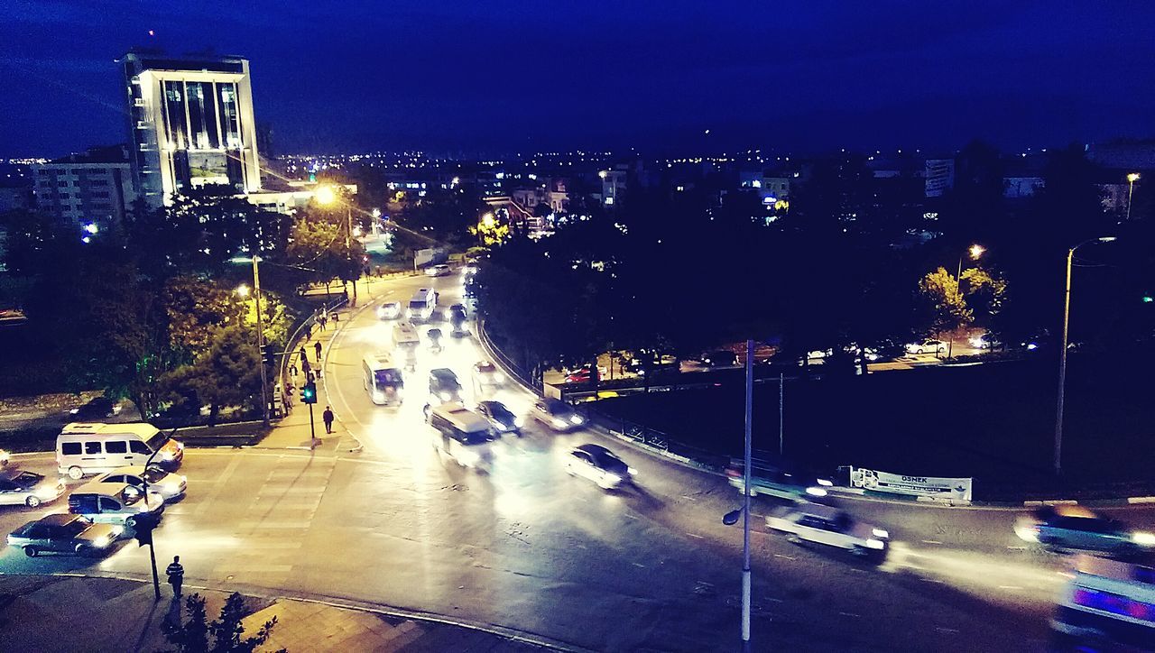 illuminated, city, building exterior, night, architecture, transportation, built structure, high angle view, cityscape, mode of transport, car, city life, land vehicle, street, road, street light, traffic, city street, sky, on the move