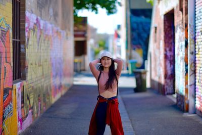 Portrait of smiling young woman against brick wall