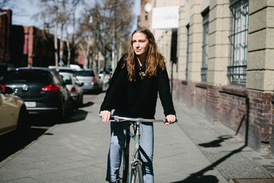 Full length of woman with bicycle on street in city