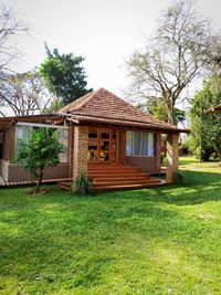 House amidst plants and trees on field against sky