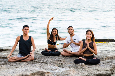 Portrait of friends doing yoga at beach