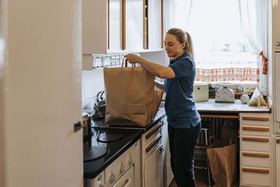 Female caregiver keeping bags on kitchen counter at home