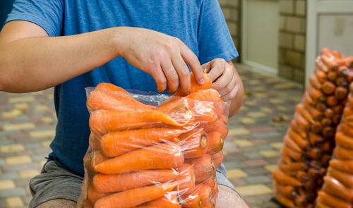 A farmer is packing freshly picked carrots into bags for sale. freshly harvested carrots.