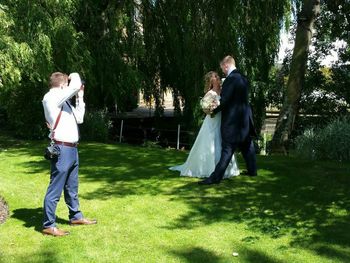 Rear view of man and daughter standing on grassy field