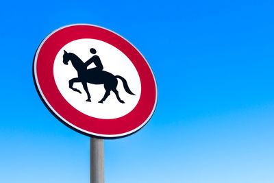 Close-up of road sign against clear blue sky