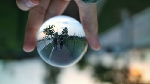 Close-up of hand holding glass with reflection