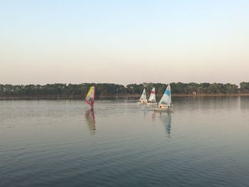 People on lake against clear sky