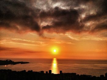 Scenic view of sea against cloudy sky at sunset