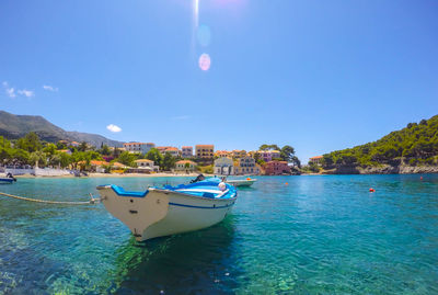 Boats moored in sea against clear blue sky