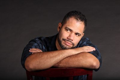 Close-up of thoughtful man sitting on chair against black background