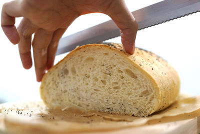 Cropped hand of person cutting bread