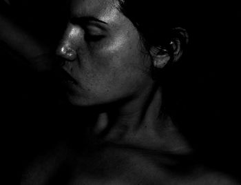 Close-up portrait of young woman against black background