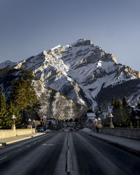 Road by snowcapped mountains against clear sky