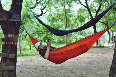 Man using mobile phone while relaxing in hammock