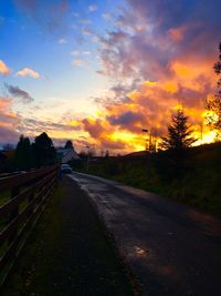 Road amidst silhouette landscape against sky during sunset