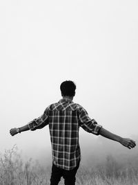 Rear view of man standing on field against clear sky