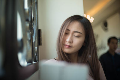 Beautiful young woman sitting by window at restaurant