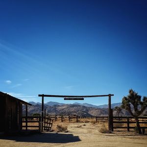 Fence on field against clear blue sky