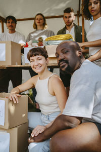 Portrait of male and female volunteer posing with team during charity drive at community center