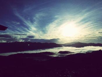 Sun shining through clouds over mountains